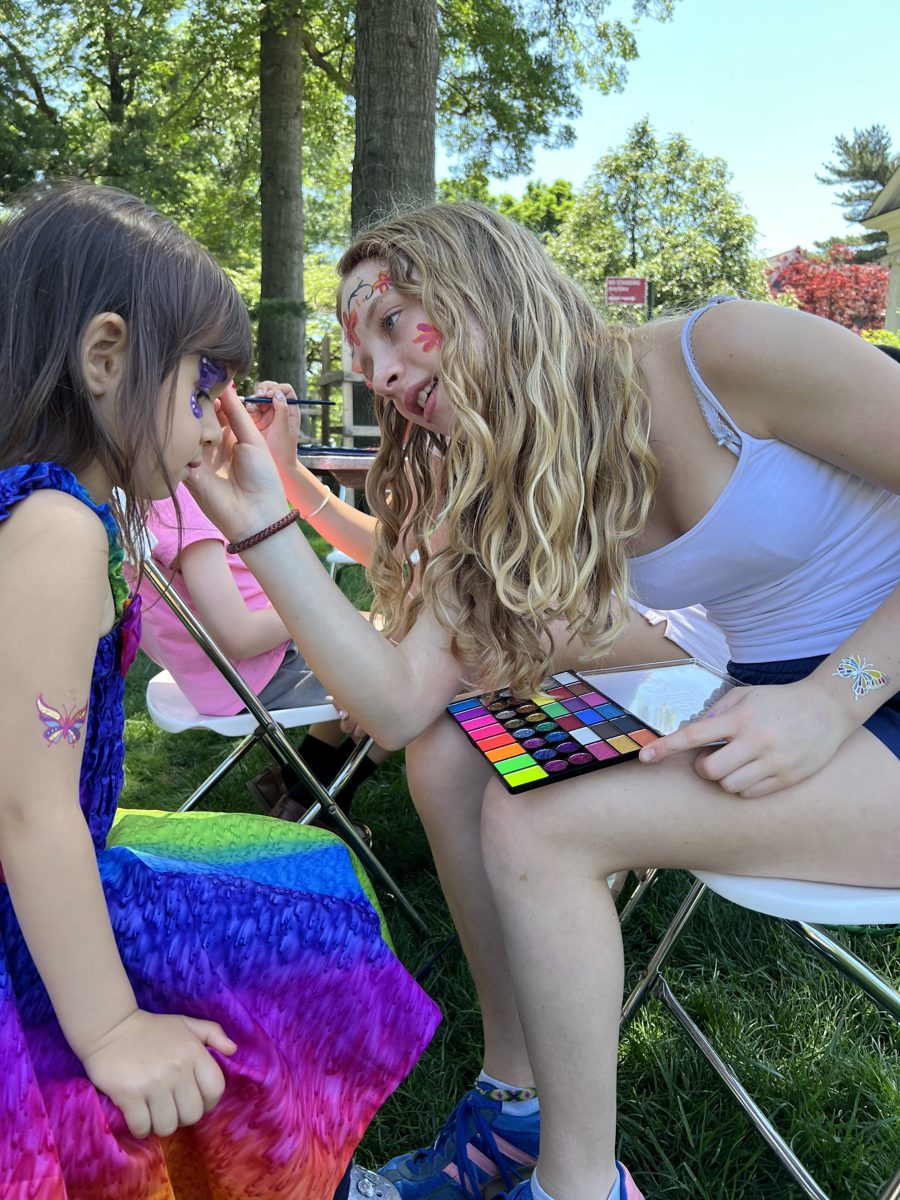 Lucy face painting a young girl's face at a community event