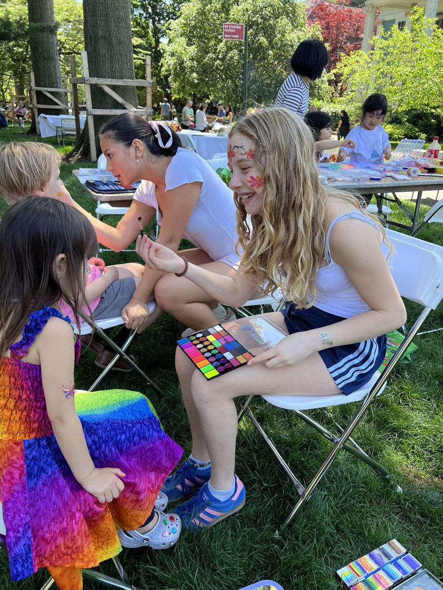 Lucy painting a flower design at an outdoor event