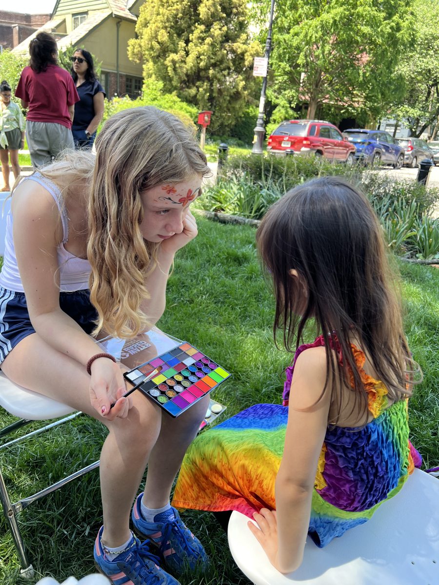 Lucy showing a finished flower face paint design to a child